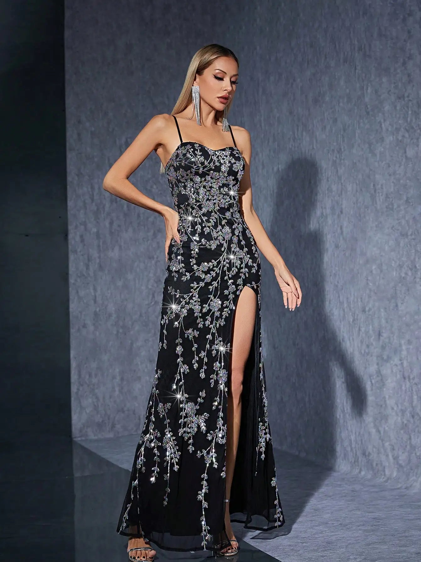 Flat lay of black slit gown with spaghetti straps and floral details

