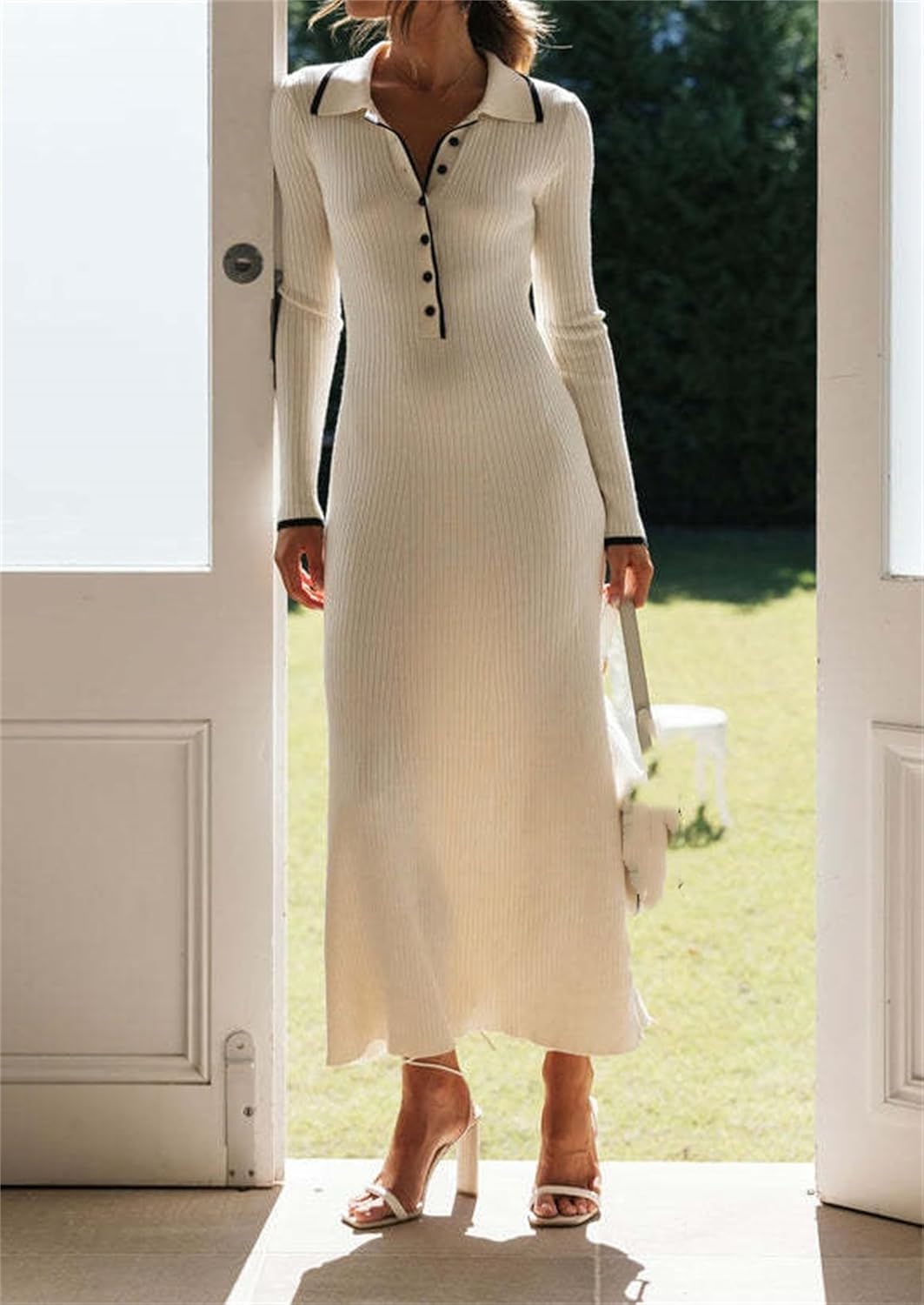 Woman wearing a maxi knitted dress with black accents, standing in a doorway.